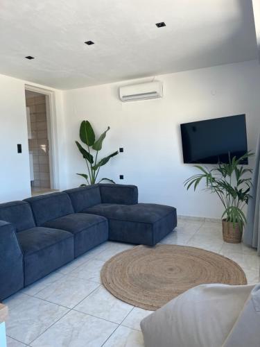 a living room with a blue couch and a flat screen tv at Elounda Port Apartment in Elounda
