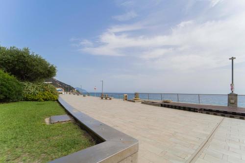 - une passerelle à côté de l'océan avec des bancs dans l'établissement 215 - Deiva al Mare, appartamento fronte mare con vista, à Deiva Marina