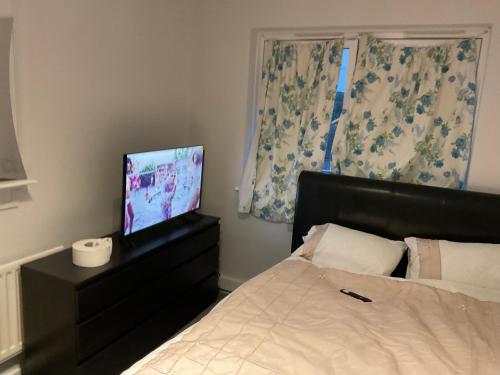 a bedroom with a bed and a flat screen tv at Road to home in Abbey Wood