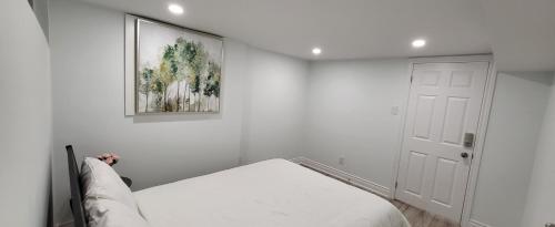 een witte slaapkamer met een bed en een schilderij aan de muur bij Queen Bedroom, Private room, separate entrance 401/404/DVP area in Toronto