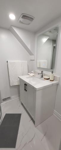 a white bathroom with a sink and a mirror at Queen Bedroom, Private room, separate entrance 401/404/DVP area in Toronto