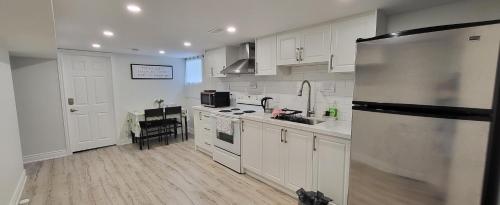 a kitchen with white cabinets and a stainless steel refrigerator at Queen Bedroom, Private room, separate entrance 401/404/DVP area in Toronto