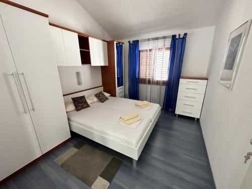 ein kleines Schlafzimmer mit einem weißen Bett und blauen Vorhängen in der Unterkunft Apartman Gaga in Kruševo