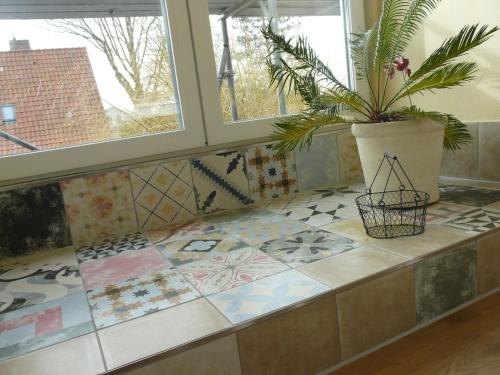 a tiled counter with a potted plant and a window at Haus am Teich - Teichblick in Fehmarn