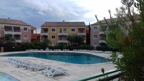 une piscine avec des chaises longues et des bâtiments dans l'établissement Appartement 4 pers. 1 chambre avec piscine, à Roquebrune-sur Argens