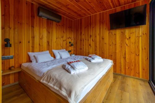 a bed in a wooden room with two pillows on it at Blackbox House Noszvaj in Noszvaj