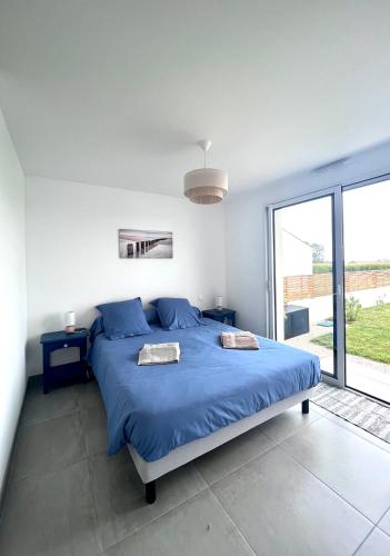 une chambre avec un lit bleu et une grande fenêtre dans l'établissement La maison du Petit Pin, à La Tranche-sur-Mer