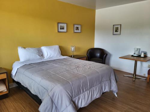 1 dormitorio con 1 cama con silla y mesa en Sherbrooke Village Inn, en Sherbrooke