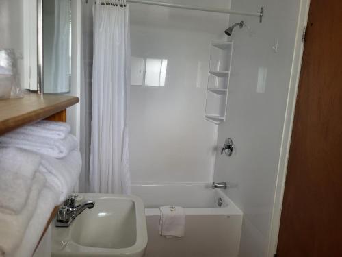 a white bathroom with a sink and a bath tub at Sherbrooke Village Inn in Sherbrooke