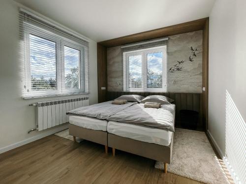 a bedroom with a bed in a room with windows at Penthouse Słoneczna Rapsodia in Rabka-Zdrój