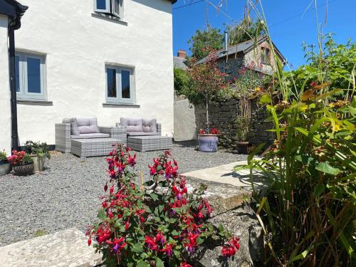 einen Garten mit roten Blumen vor einem Haus in der Unterkunft Stunning Cottage Close to Amazing Beaches in Braunton