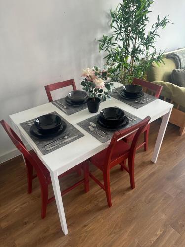 a white table with four chairs and black bowls on it at Entire 2 bedroom flat in London