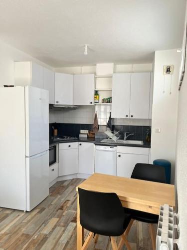 a kitchen with a wooden table and white cabinets at Appartement Centre Annemasse, direct tram Geneve in Annemasse