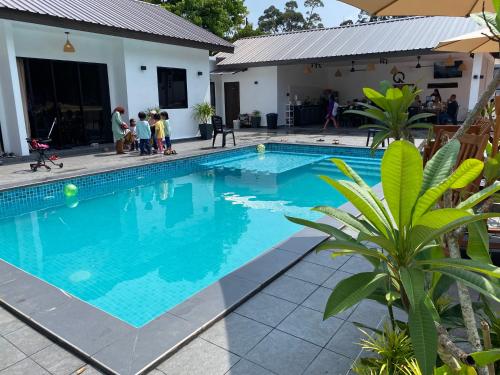 a swimming pool with people standing around it at Villa The Quarry Segamat in Segamat