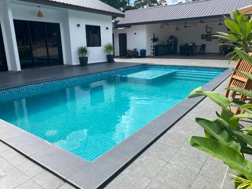 a swimming pool with blue water in front of a house at Villa The Quarry Segamat in Segamat