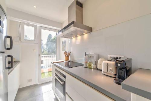 une cuisine blanche avec un comptoir et une fenêtre dans l'établissement ROSE DES SABLES, à Antibes