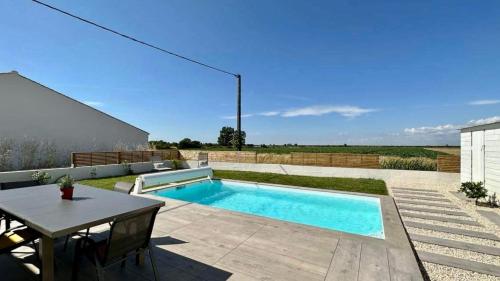 - une piscine dans une cour avec une table et une table dans l'établissement La maison du Petit Pin, à La Tranche-sur-Mer