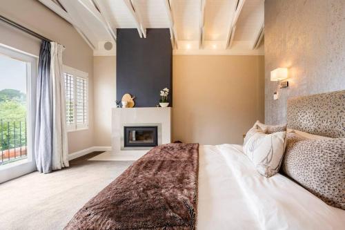 a bedroom with a bed and a fireplace at Luxe Family Home with Solar Power in Secure Hout Bay Estate in Cape Town