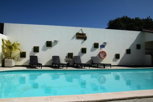 uma parede branca com cadeiras e uma piscina em Casa Vereda, Ponta Delgada, S. Miguel em Ponta Delgada