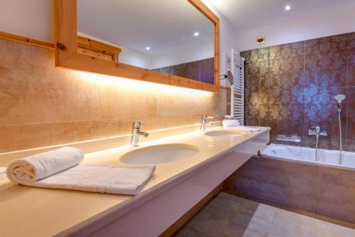 a bathroom with two sinks and a bath tub at Cerana Relax Hotel in Madonna di Campiglio