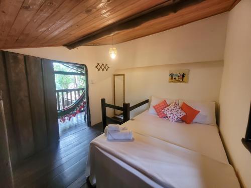 a bedroom with a white bed and a window at Pousada Raiz Forte in Caraíva