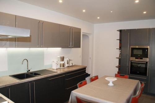 une cuisine avec des placards noirs et une table avec un évier dans l'établissement Le Prieuré: maison de charme proche de Vézelay****, à Asnières-sous-Bois