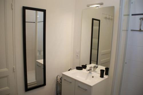 ein weißes Badezimmer mit einem Waschbecken und einem Spiegel in der Unterkunft Le Prieuré: maison de charme proche de Vézelay**** 