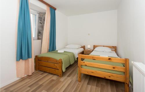 2 aparte bedden in een slaapkamer met blauwe gordijnen bij 3 Bedroom Stunning Home In Tijarica in Vukići
