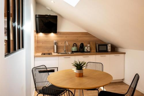 een keuken en eetkamer met een houten tafel en stoelen bij Appart-hôtel de standing avec jacuzzi privatisable en option in Périgueux