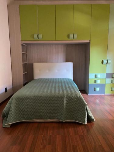 1 dormitorio con 1 cama con paredes verdes y suelo de madera en Gabe, en Cesena