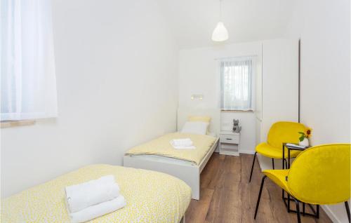 een kamer met 2 bedden en gele stoelen bij 3 Bedroom Lovely Home In Jurdani in Jurdani
