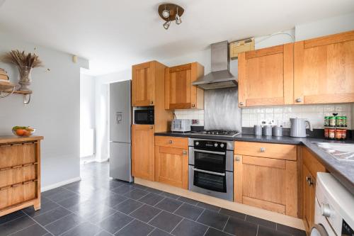 uma cozinha com armários de madeira e um forno com placa de fogão em Chelmsford Reach 3 bed house near centre,free parking, Wi-Fi, table football em Chelmsford