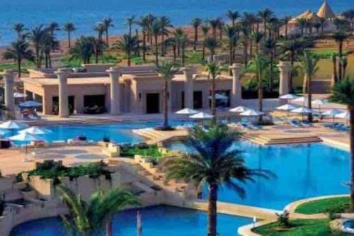 a resort with a large swimming pool with palm trees at Home in Marassi in El Alamein