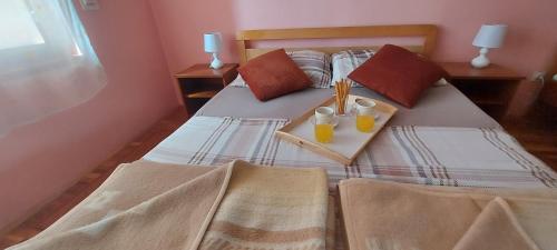 a bedroom with a bed with two glasses of orange juice at Holiday house and apartments Vale in Duga Resa