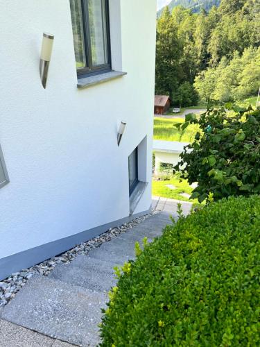 a building with a window next to a garden at 2-Zimmer Ferienwohnung an ruhiger Lage in Triesenberg