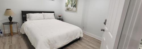 een witte slaapkamer met een bed met witte lakens bij Queen Bedroom, Private room, separate entrance 401/404/DVP area in Toronto