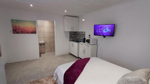 sypialnia z łóżkiem i telewizorem na ścianie w obiekcie Ozizi Lodge w mieście East London