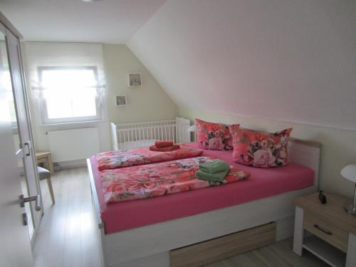 a bedroom with a bed with pink sheets and pillows at Ferienwohnung Bienwald mit Pool für 4 - 6 Personen mit 3 Schlafzimmern in Gröbitz