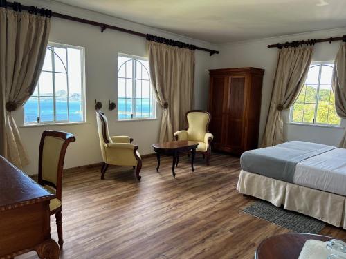 a hotel room with a bed and chairs and windows at Beau Séjour Hotel in Victoria
