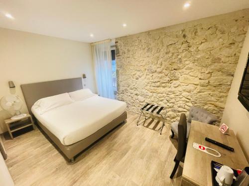 a bedroom with a bed and a stone wall at Hotel de la Couronne in Aix-les-Bains