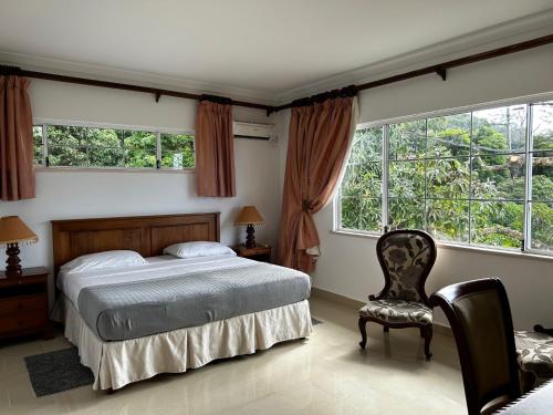 Schlafzimmer mit einem Bett, einem Stuhl und Fenstern in der Unterkunft Beau Séjour Hotel in Victoria