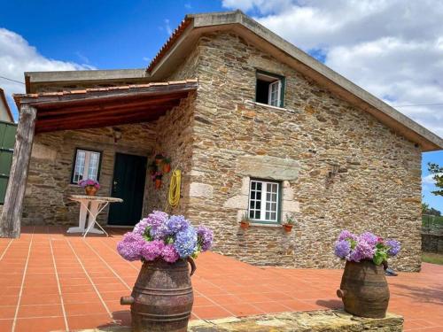 a stone house with flowers in front of it at Casa de Cotas in Cotas