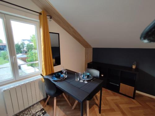 une salle à manger avec une table noire et une fenêtre dans l'établissement 4 studios - Musique en Champagne, à Châlons-en-Champagne