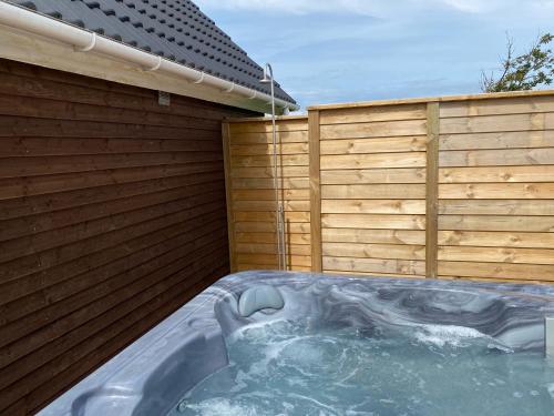 a hot tub in a backyard with a wooden fence at Løkken Klit Camping & Cottage Village in Løkken