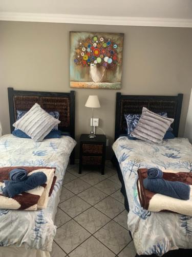 a bedroom with two beds and a painting on the wall at Rustic red in Benoni