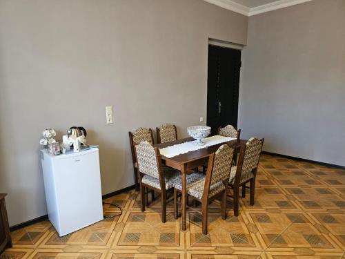 a dining room with a table and chairs and a refrigerator at Guest House AMO in Kutaisi