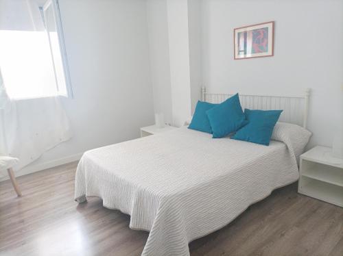 Dormitorio blanco con cama con almohadas azules en Apartamento Pinar de Chamartin en Madrid