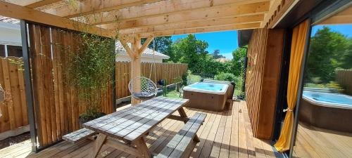 une terrasse en bois avec un banc et une baignoire. dans l'établissement Les Bord'Océanes Sauna & Spa Villa Marensine et Villa Oyat, à Vielle-Saint-Girons