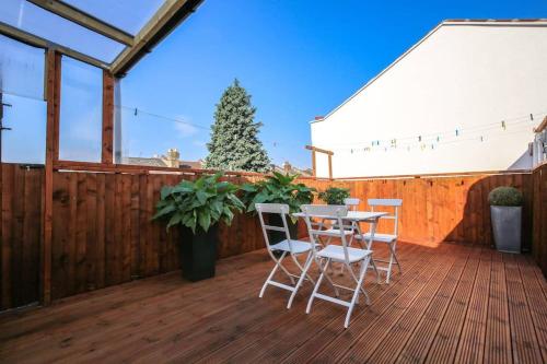 a patio with a table and chairs on a wooden deck at Large Modern Apartment with Garden Sleeps 10 Guests in London