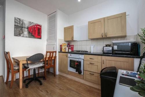 a kitchen with wooden cabinets and a table and a table and chairs at Large Modern Apartment with Garden Sleeps 10 Guests in London